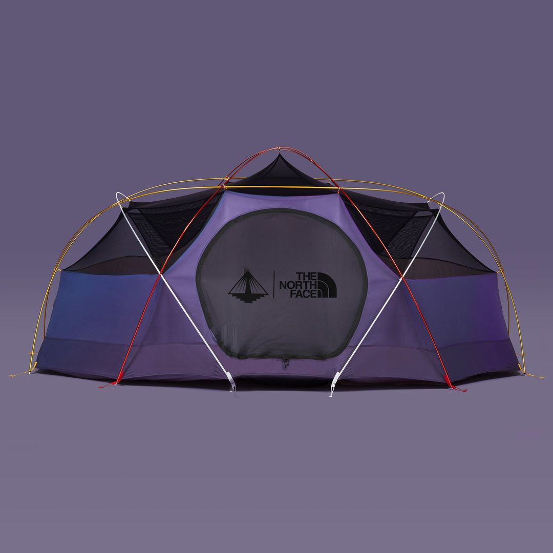 A Nomadic North Face Oval Intention | Event Collaboration tent - Used, dome-shaped with black mesh panels, yellow and red poles, The North Face logo on front, set against a plain purple background.